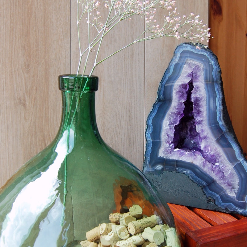 Décoration d'intérieur : belle géode d'améthyste d'Uruguay avec une bonbonne en verre contenant des fleurs