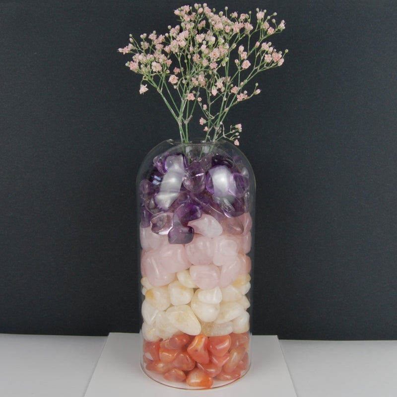 Composition de décoration d'intérieur : fleurs dans un vase en verre rempli de pierres roulées naturelles multicouleurs